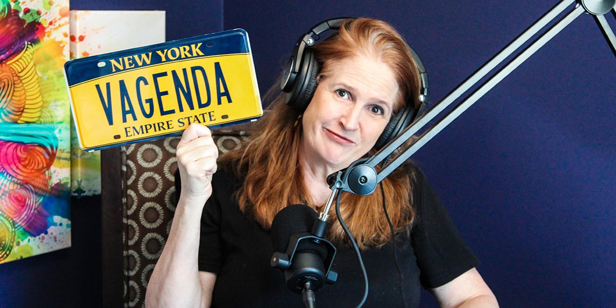 Joanne Secky, Natural Born Red Head, holding a NY license plate that reads 'VAGENDA'.